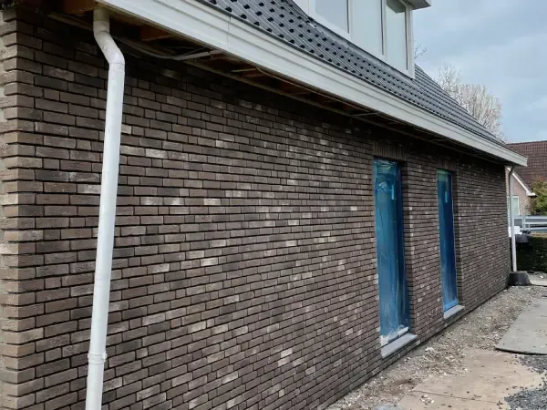 Woonhuisgevel met bruine steenstrips na gevelisolatie