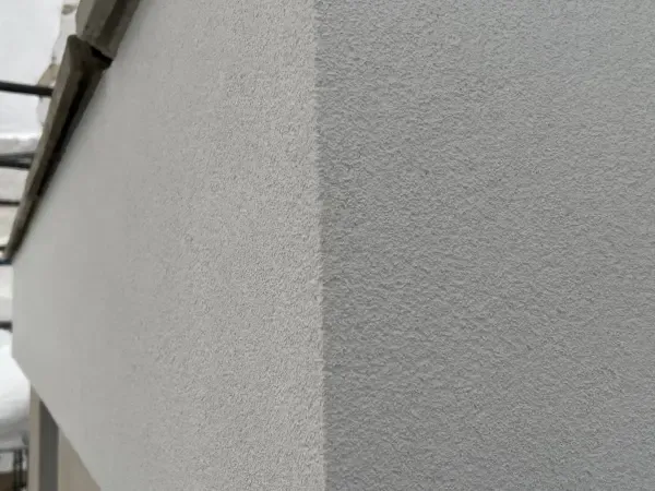 Detail van strak grijs sierpleisterwerk op een gevelhoek