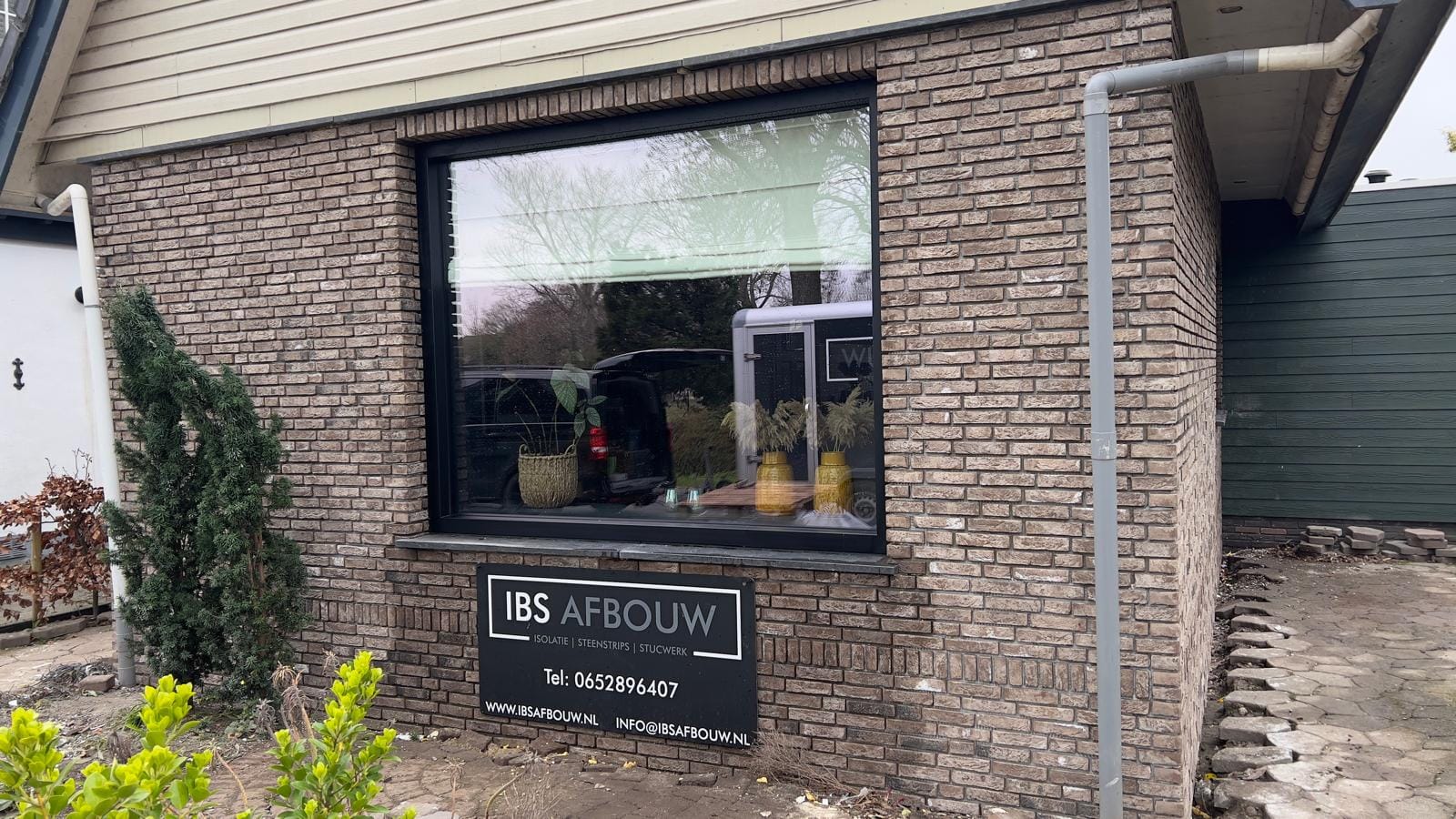 Gevel met grijsbruine steenstrips en IBS Afbouw-bord na renovatie in Andijk
